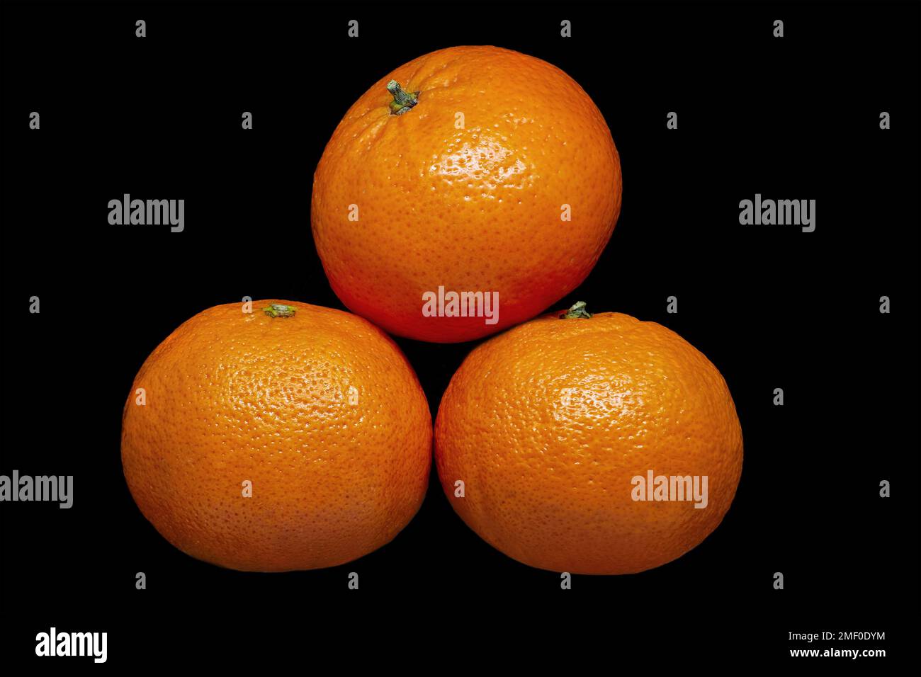 Image of three ripe tangerines on black background Stock Photo