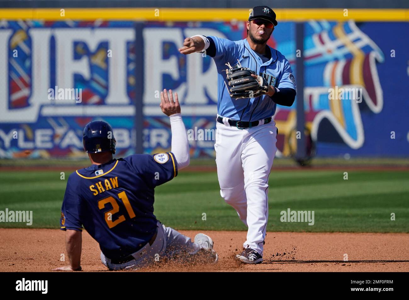 Seattle Mariners third baseman Ty France, right, blows a bubble as he  forces out Milwaukee Brewers' Travis Shaw at second base and completes the  throw to first on a fielder's choice hit