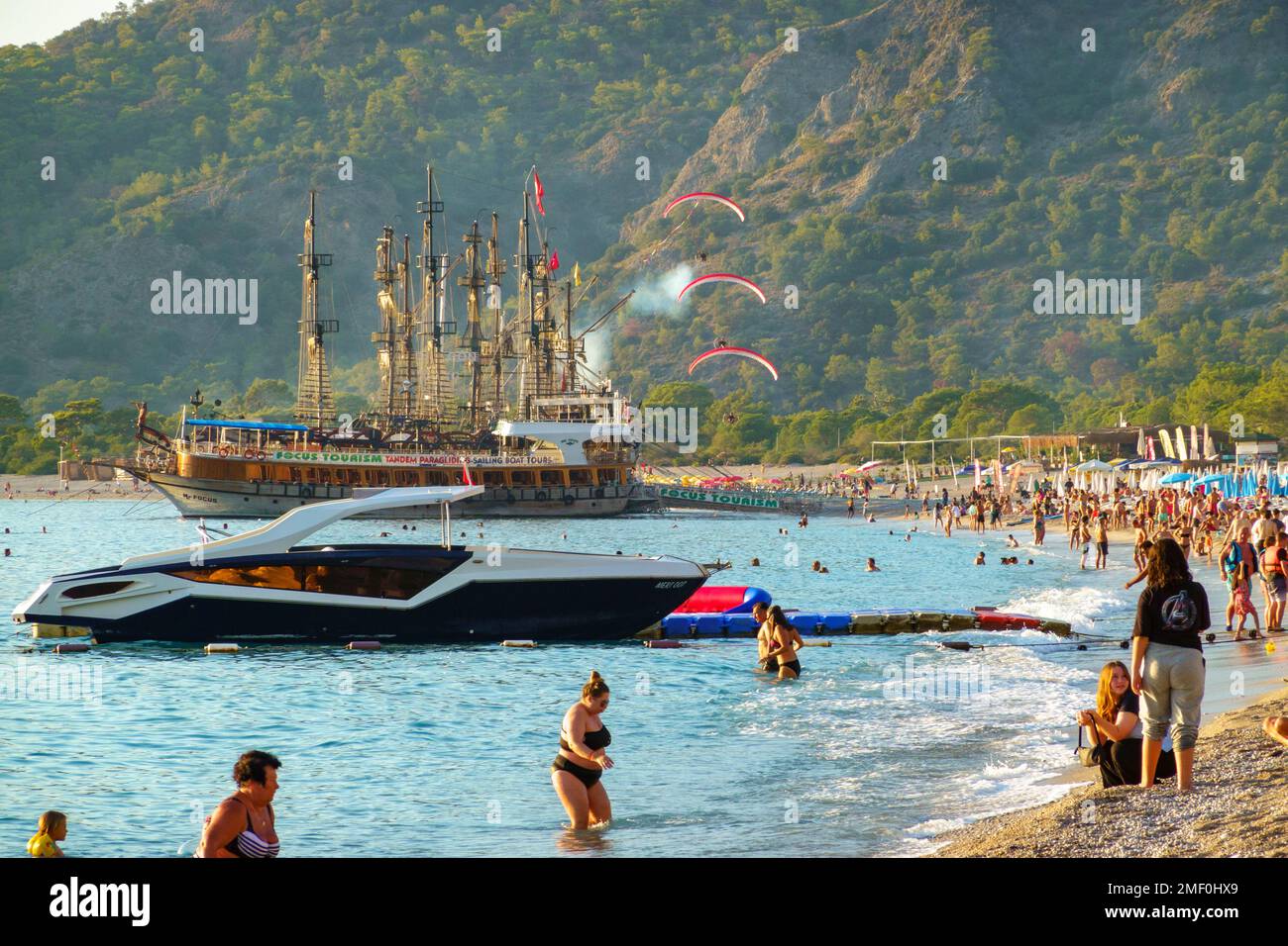 Paramotor pilots flying over boats and beachgoers in Belcekiz Beach, Oludeniz, Fethiye, Turkey Stock Photo