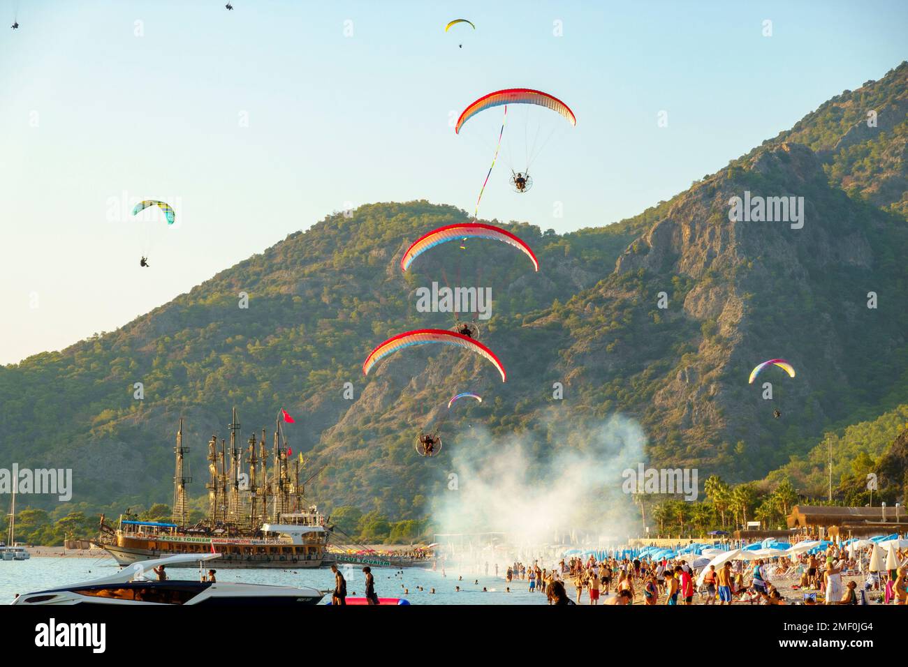 Paramotor pilots flying over boats and beachgoers in Belcekiz Beach, Oludeniz, Fethiye, Turkey Stock Photo