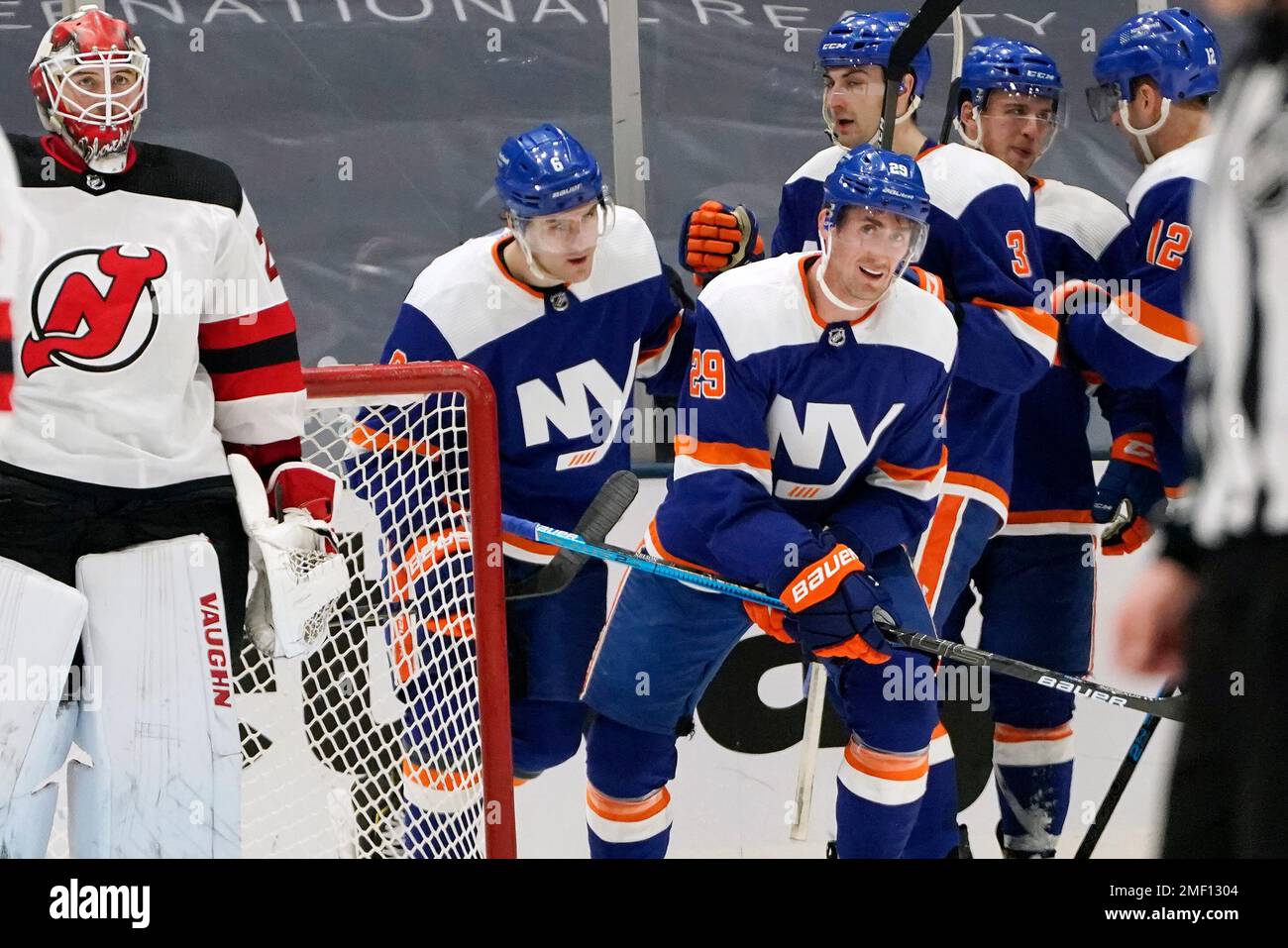 New Jersey Devils goaltender Mackenzie Blackwood, left, looks at a video replay above the ice as New York Islanders center Brock Nelson (29) and defenseman Ryan Pulock (6) skate toward the bench