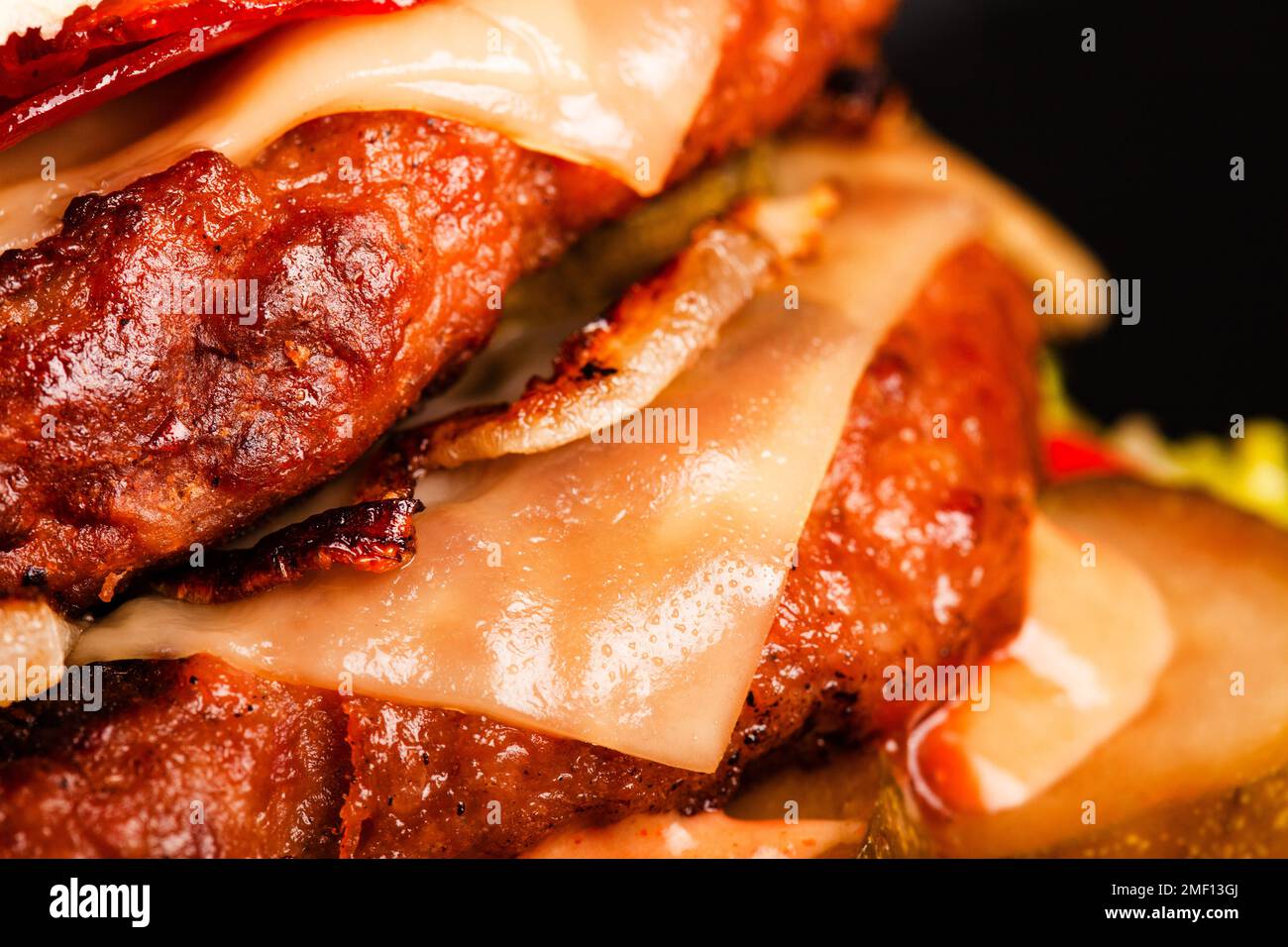 Abstract double burger with bacon cheese onions tomatoes cucumber. Against dark background. Stock Photo