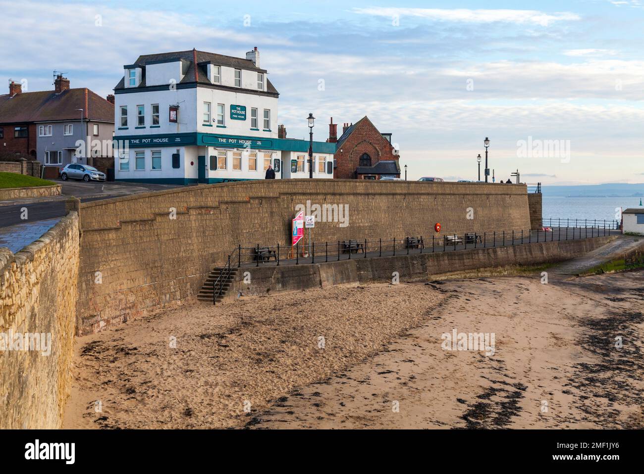 The beach and sea wall at Hartlepool Headland, England, UK with the Pot and Glass pub in background. Stock Photo