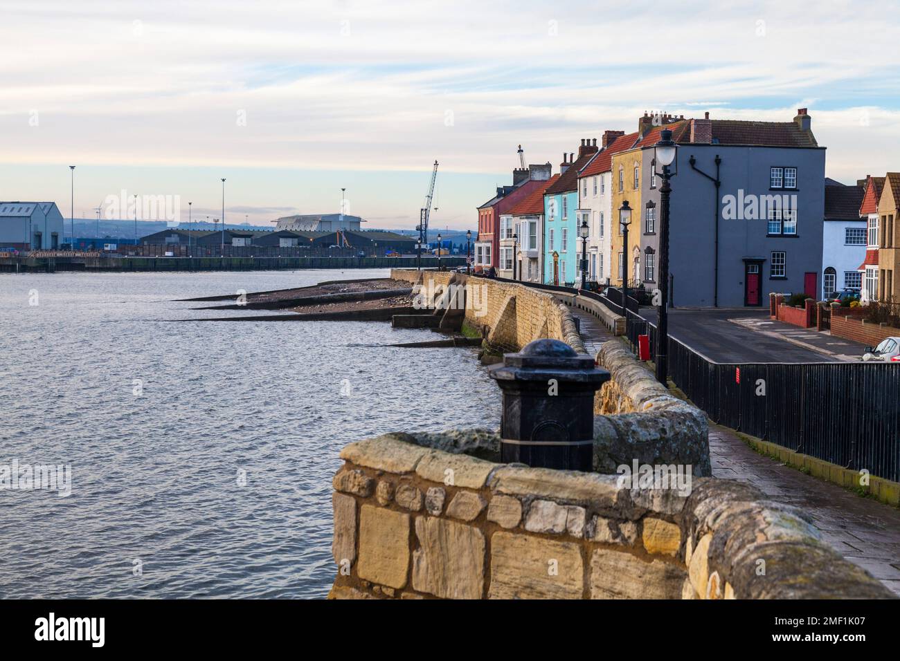 The beach,sea walls and houses with the cranes in the background at the Headland,Old Hartlepool,England,UK Stock Photo