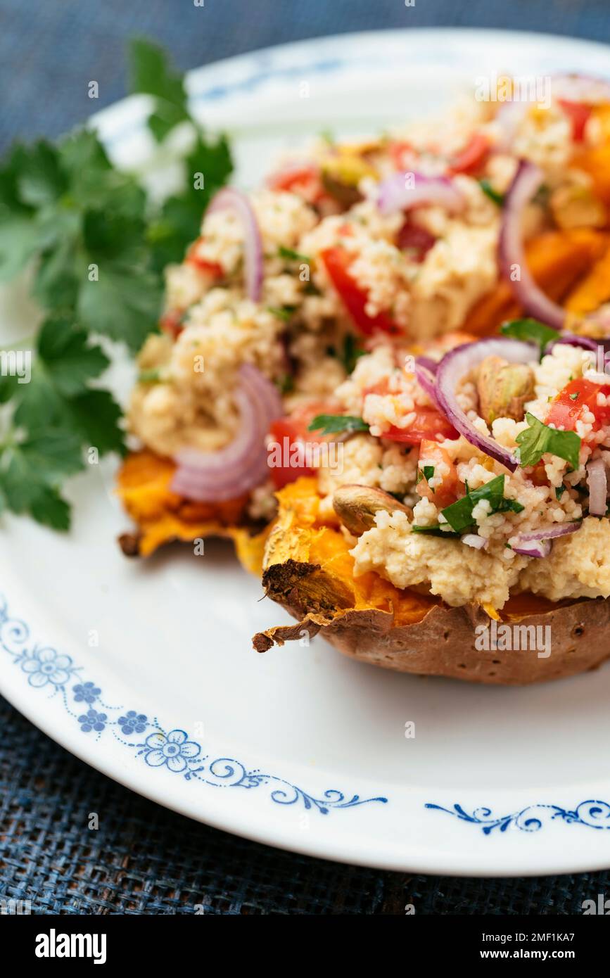 Sweet potatoes loaded with chickpea hummus and tabouleh couscous. Stock Photo