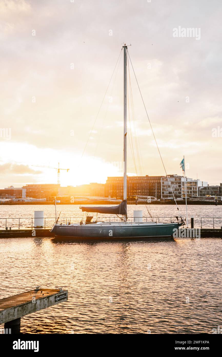 A vertical shot of a pier and a parked boat during scenic sunset in the ...
