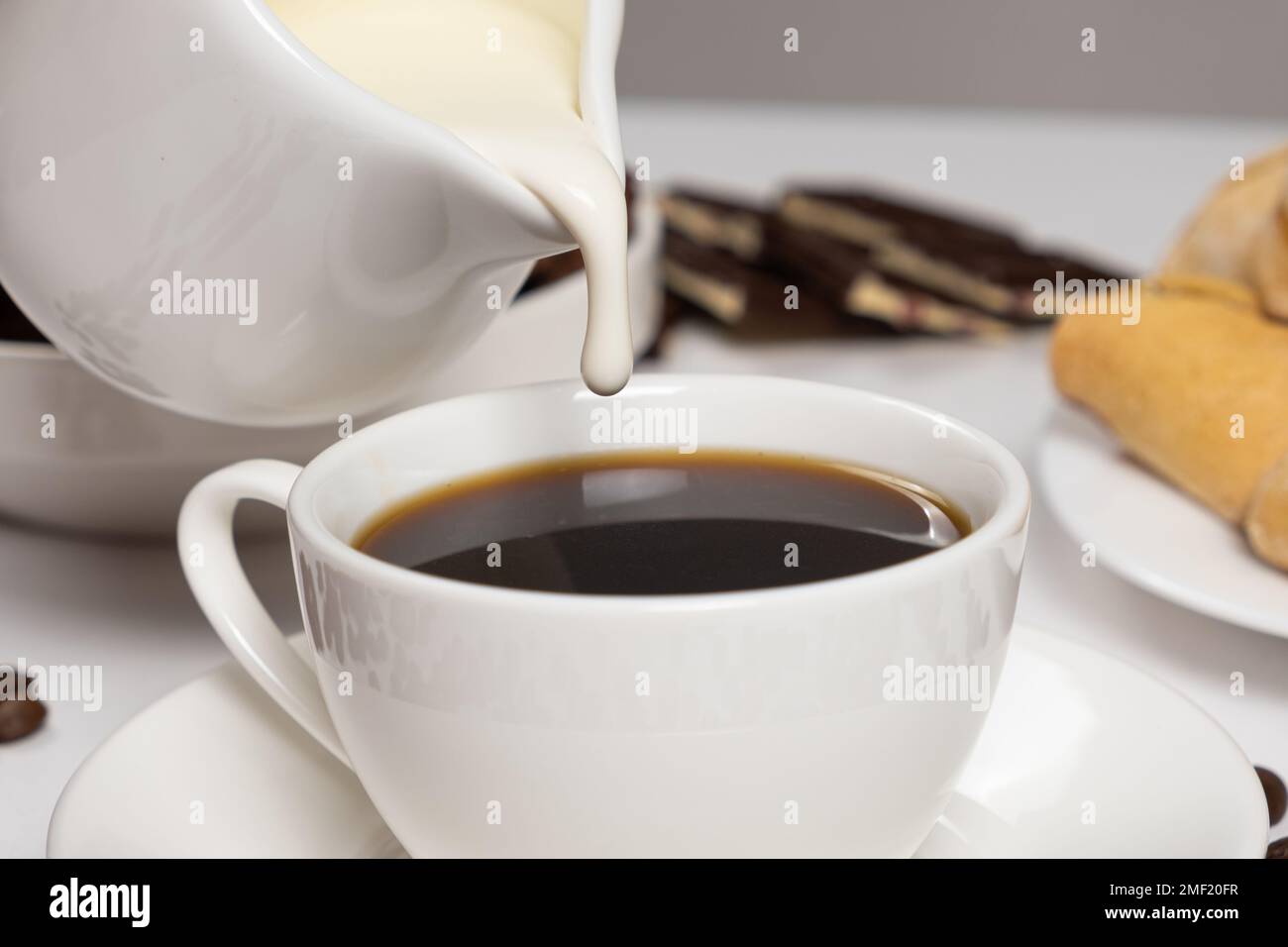 Cream from the milk jug is poured into coffee, making coffee with cream