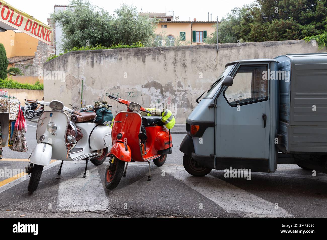 Two vintage vespas parked in front of Ape Italian pickup truck, Pisa, Tuscany, Italy. Stock Photo