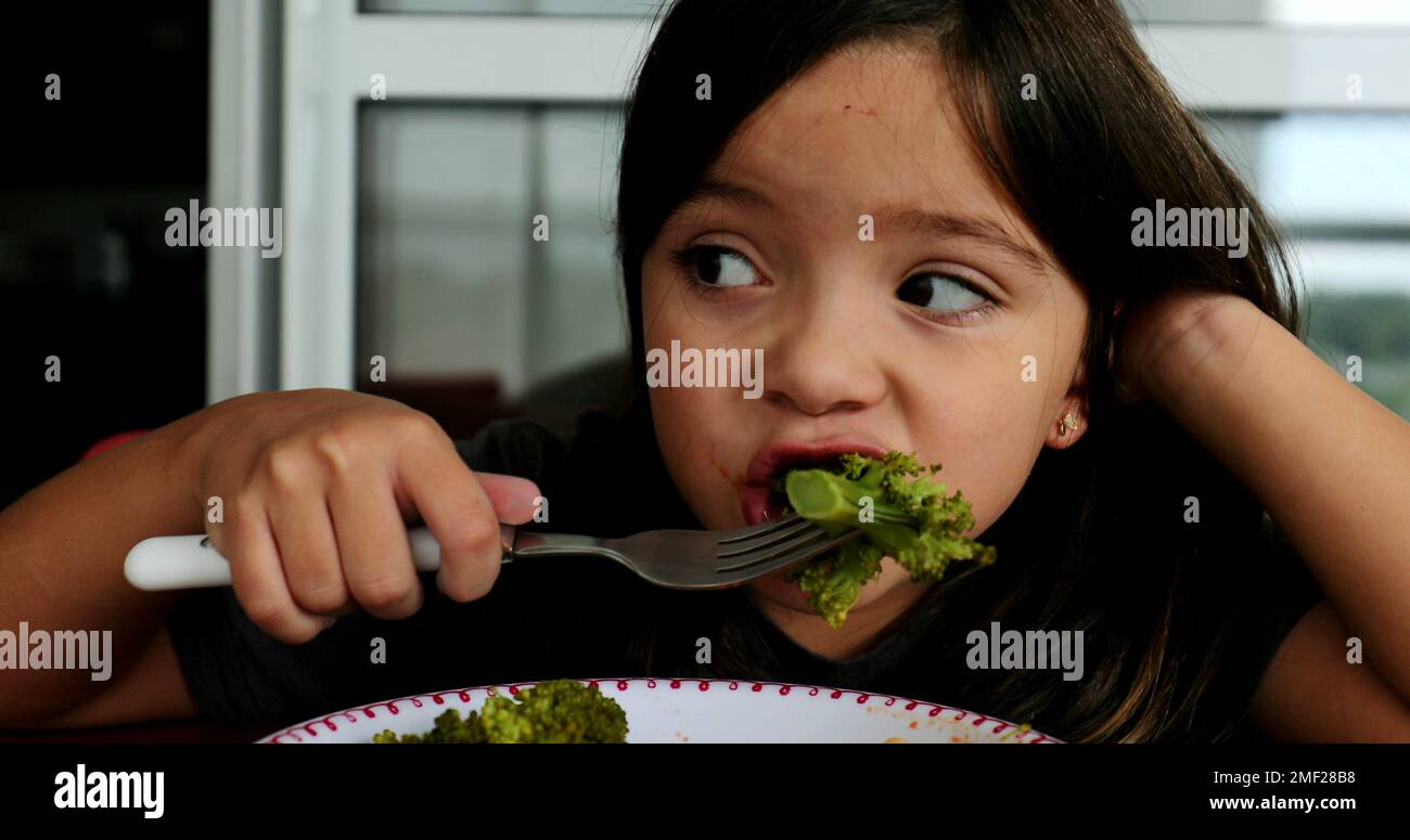 Child eating broccoli for lunch small girl eats healthy vegetable meal