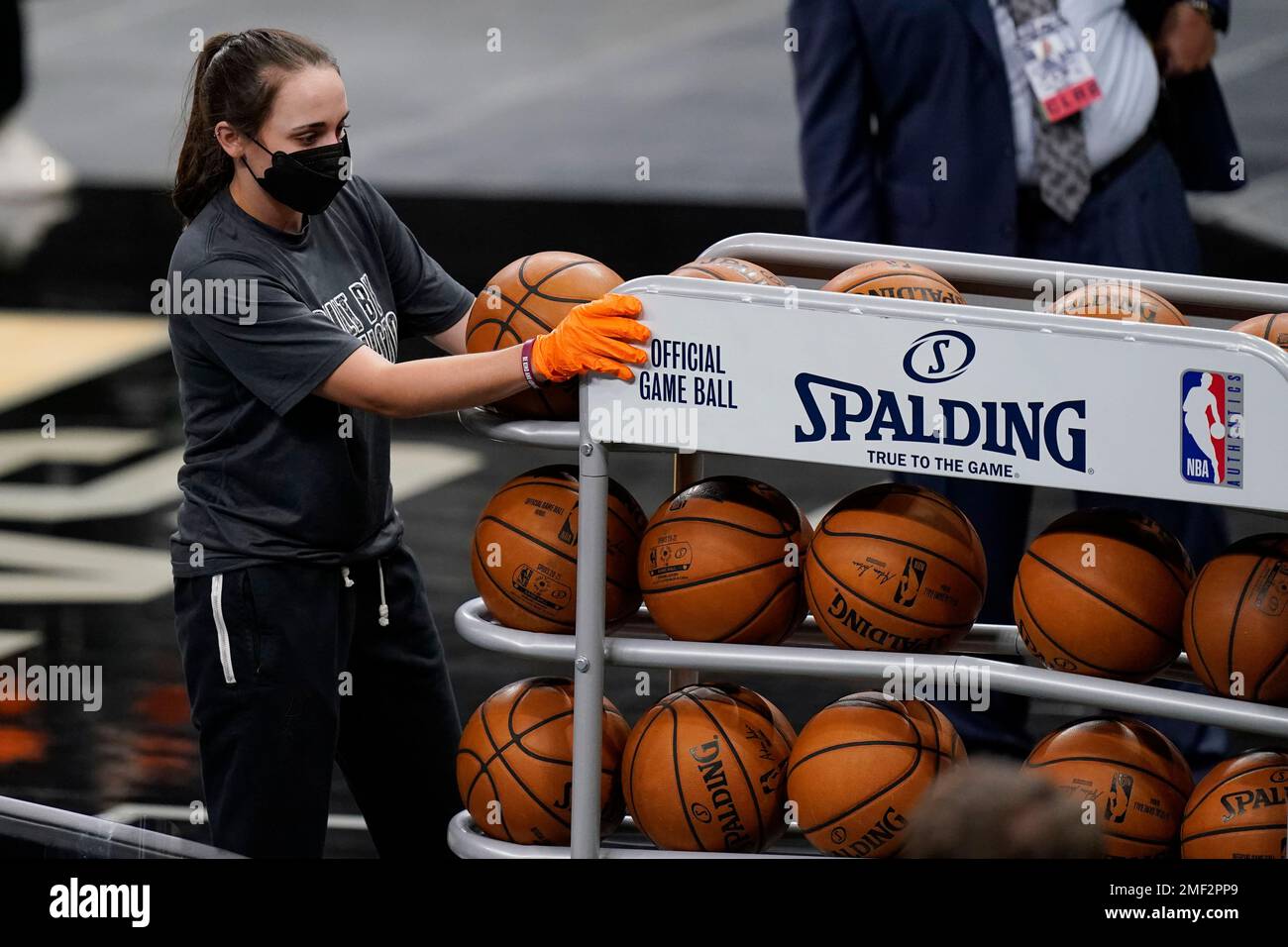 A San Antonio Spurs team attendant uses protective gear as she moves ball  off the court prior to an NBA basketball game between the San Antonio Spurs  and the New Orleans Pelicans