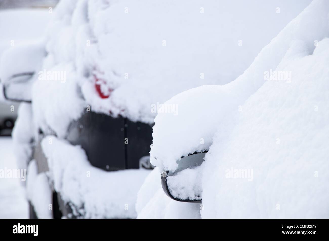 Parked cars on the roadside along the houses in the morning on the street in the city in the snow, the city of Dnipro in Ukraine, winter weather in th Stock Photo