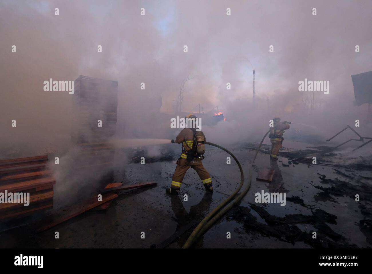 Firefighters battle a fire at a commercial yard in Compton, Calif., on ...