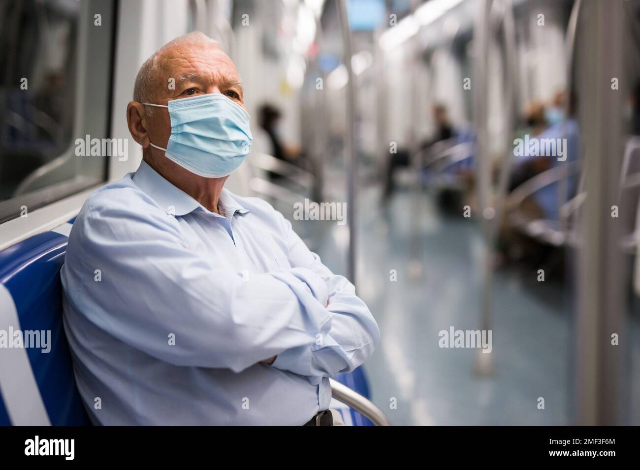 Old man in face mask sitting inside subway train Stock Photo