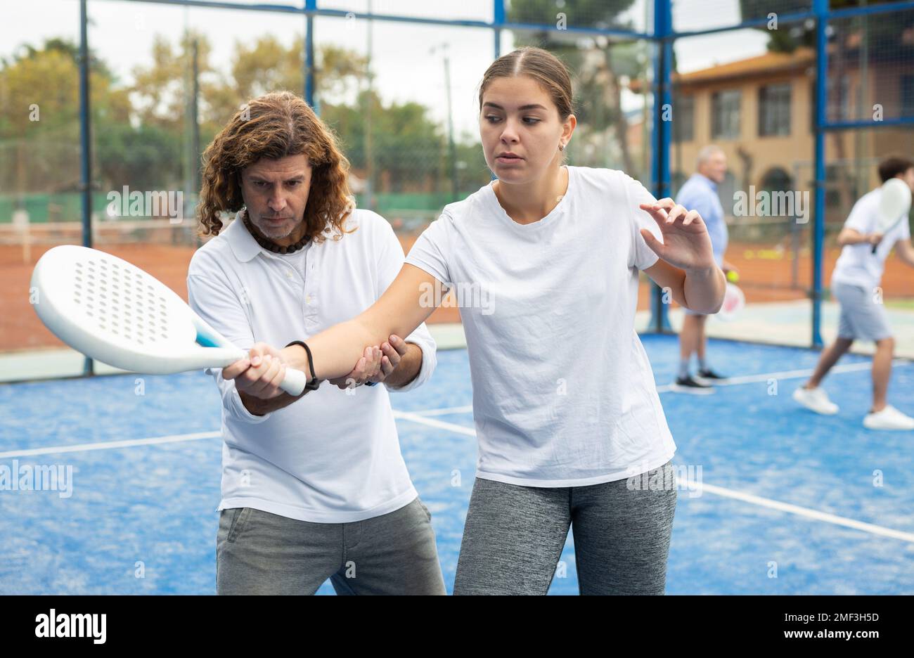 Paddle tennis coach giving lessons to girl on outdoor court Stock Photo Alamy