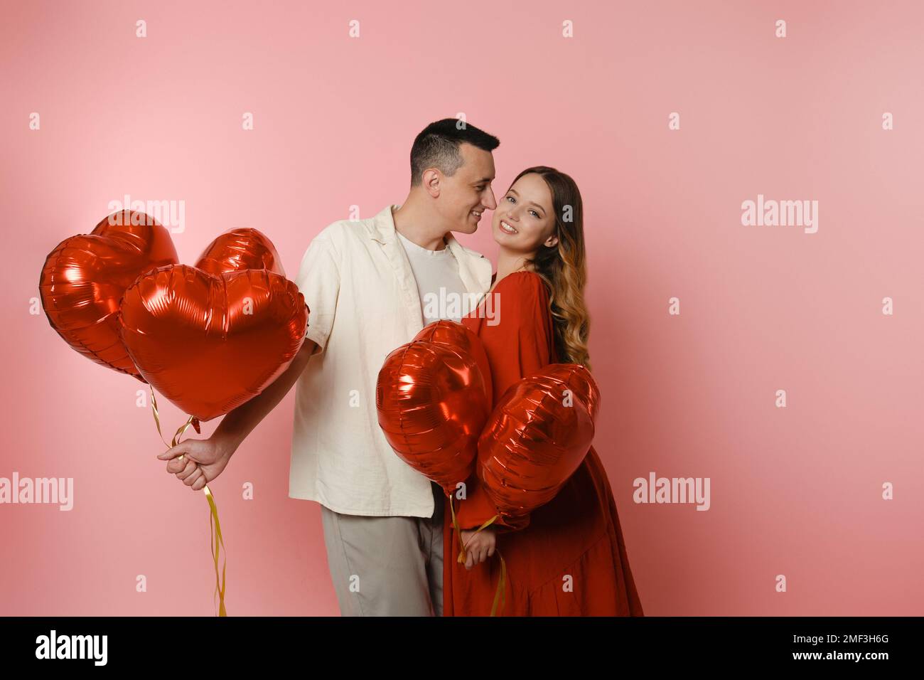 Couple, red balloons in the shape of a heart on a pink background ...