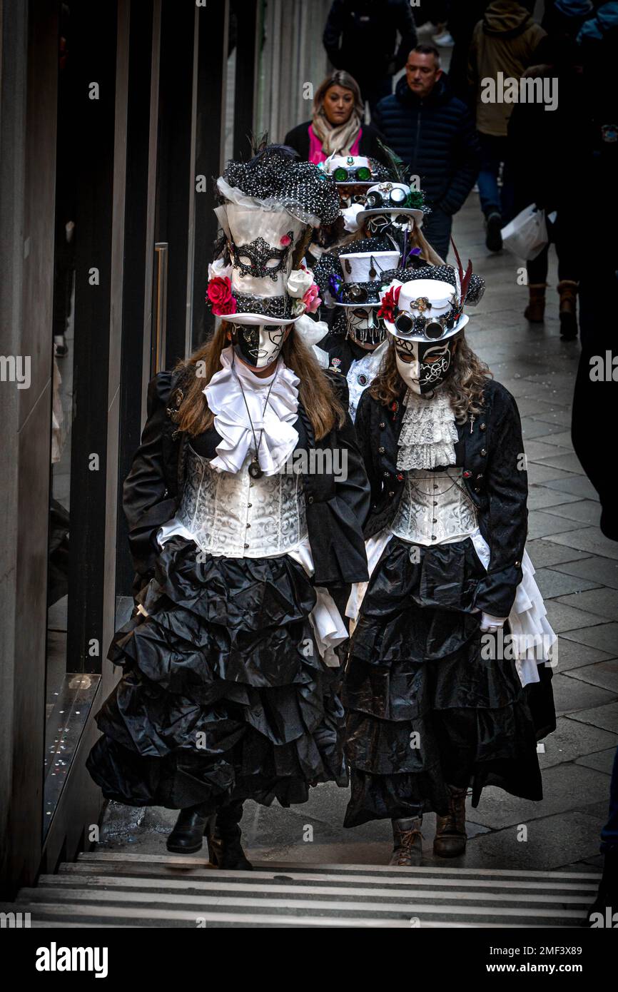 A group of girls dressed in medieval dresses and carnival masks walk down the street in Venice, Italy Stock Photo
