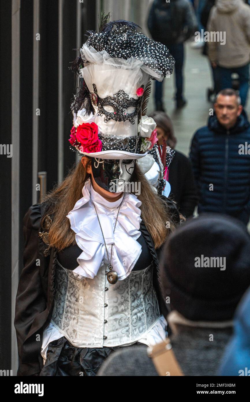 A girlwearing medieval dress and black and white carnival mask walk down the street in Venice, Italy Stock Photo