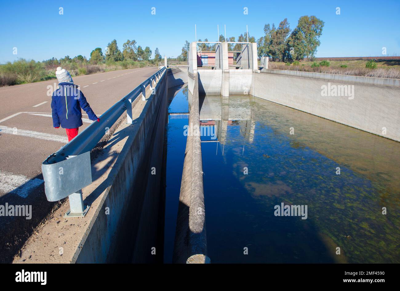 Orellana Irrigation canal in winter. Child boy getting close to regulation dam, Extremadura, Spain Stock Photo
