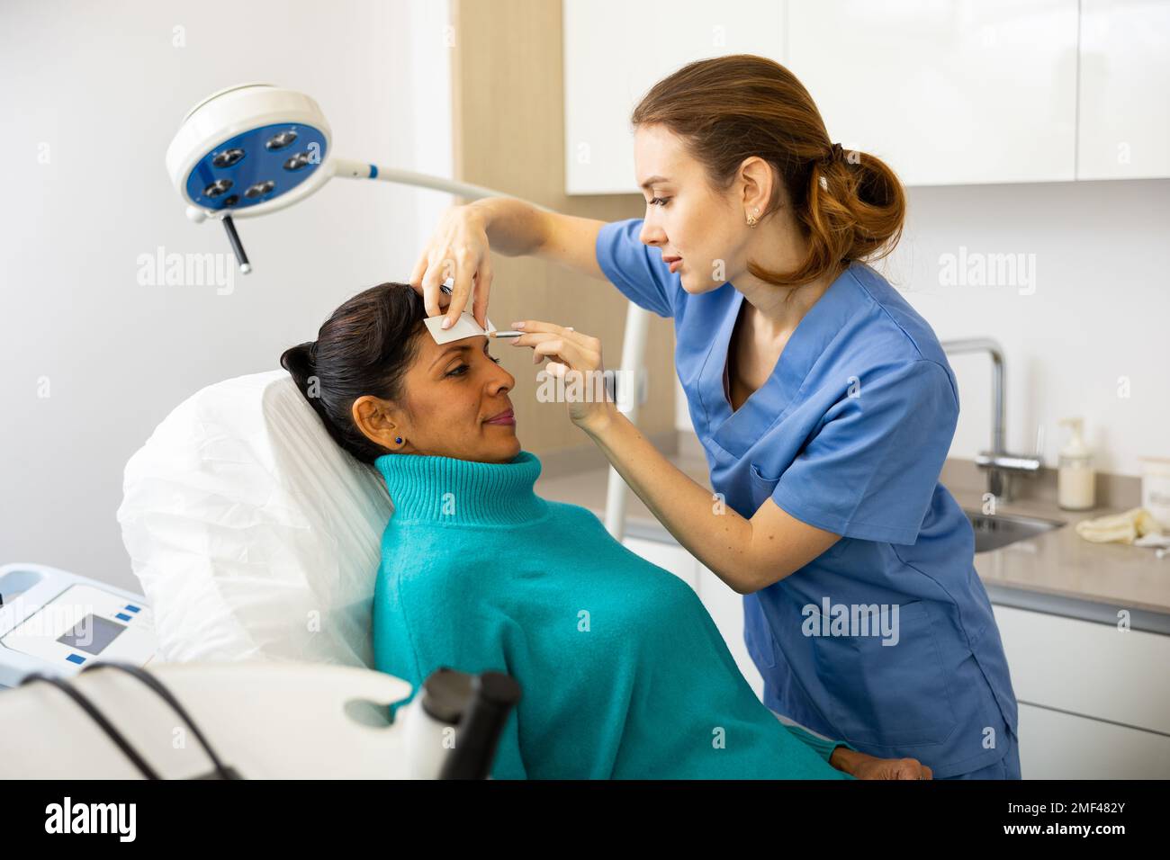 Beautician drawing correction lines on woman face Stock Photo