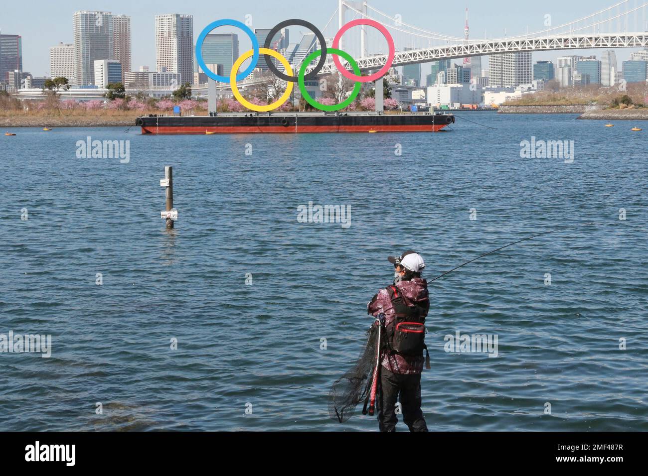 An angler enjoys fishing with he Olympic rings floating in the water in