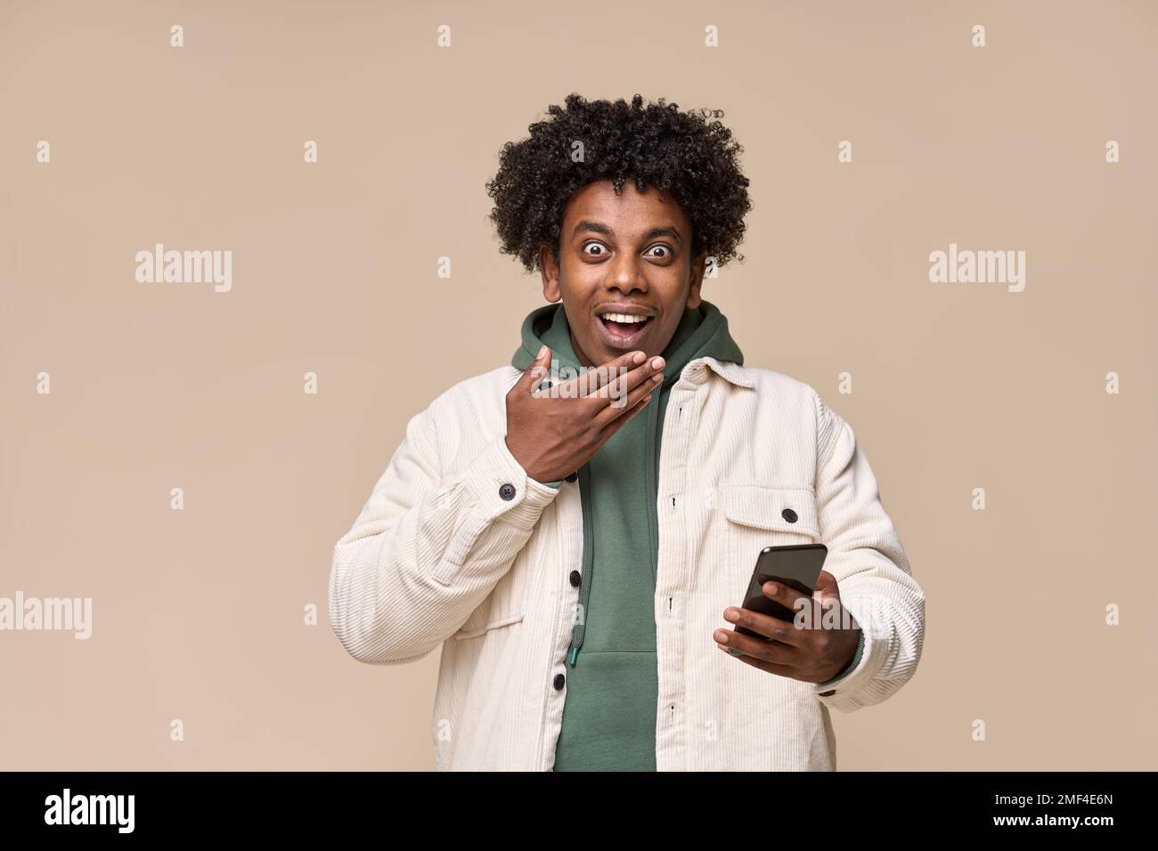 Excited surprised African teen using mobile phone feeling amazed. Stock Photo