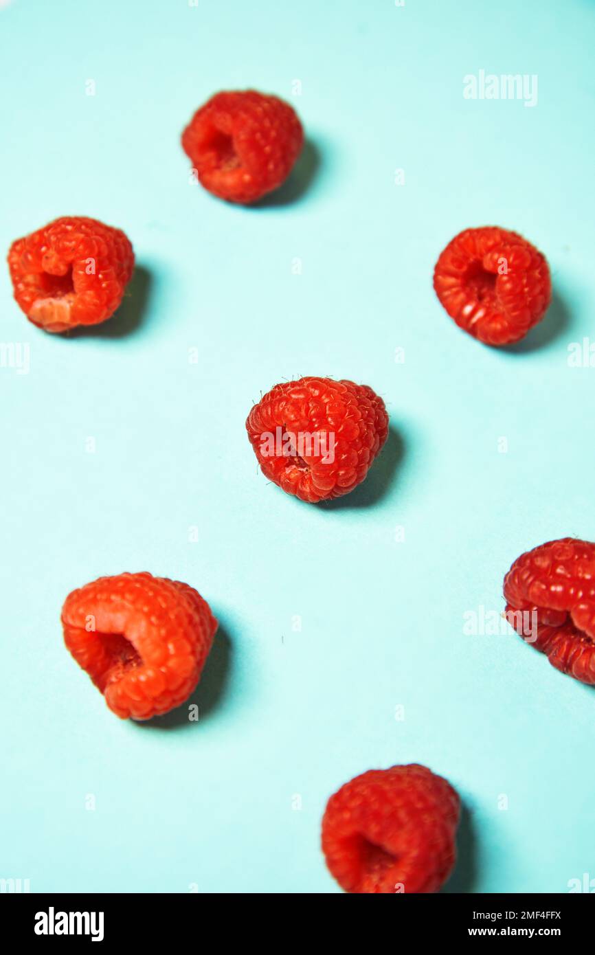 Raspberry pattern on the blue color of the lagoon. Fruits and healthy food, trendy photo Stock