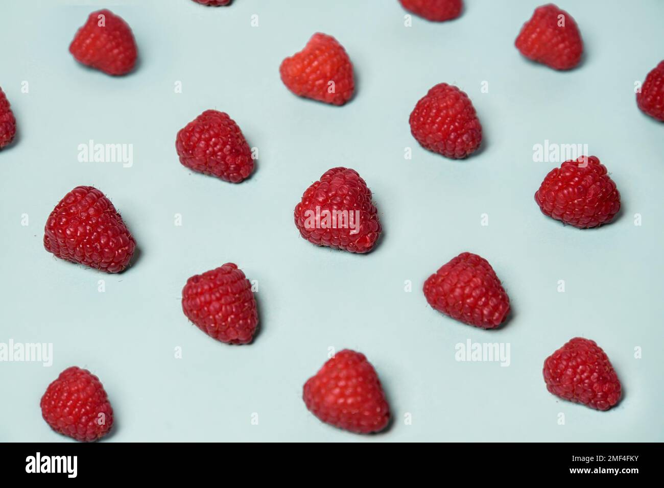 Raspberry pattern on the blue color of the lagoon. Fruits and healthy food, trendy photo Stock