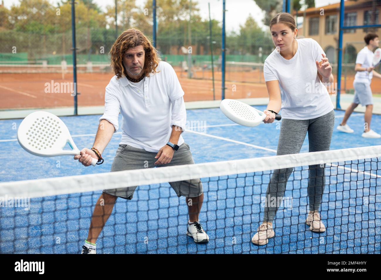 Paddle tennis coach giving lessons to girl on outdoor court Stock Photo Alamy