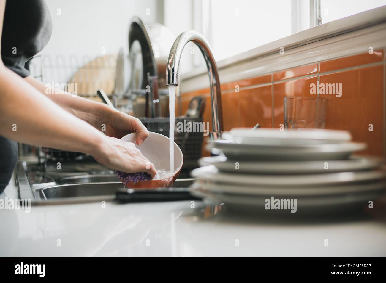 Woman washing dishes in kitchen sink, close up of hands while cleaning Stock Photo