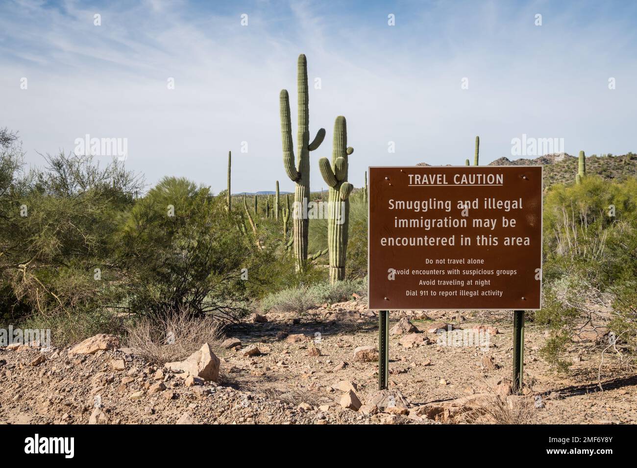 Sign near US - Mexican border wall reading Caution smuggling and illegal immigration in this area - Arizona Stock Photo