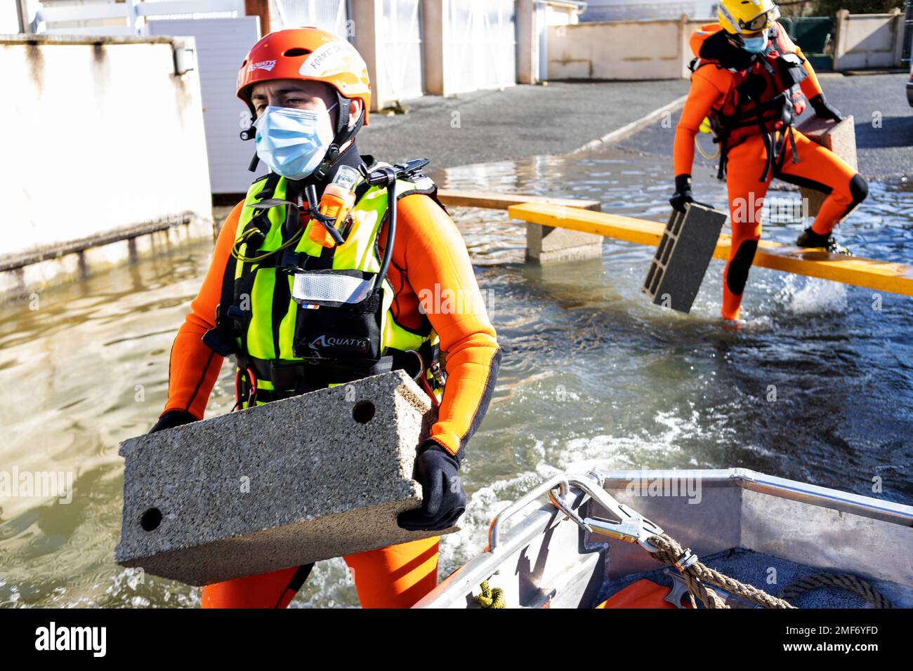 Rescue workers carry cinder blocks to build gateways in a flooded ...