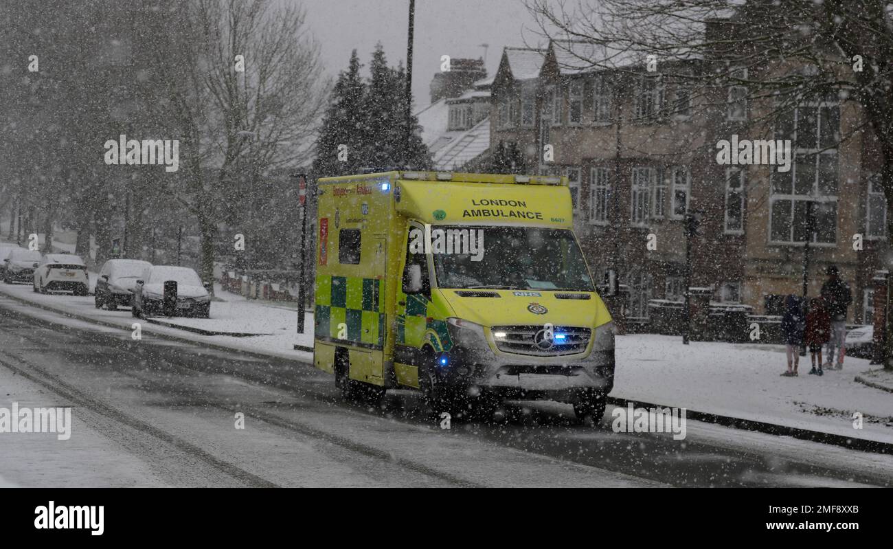 An emergency ambulance drives through heavy snow fall in London, Sunday ...