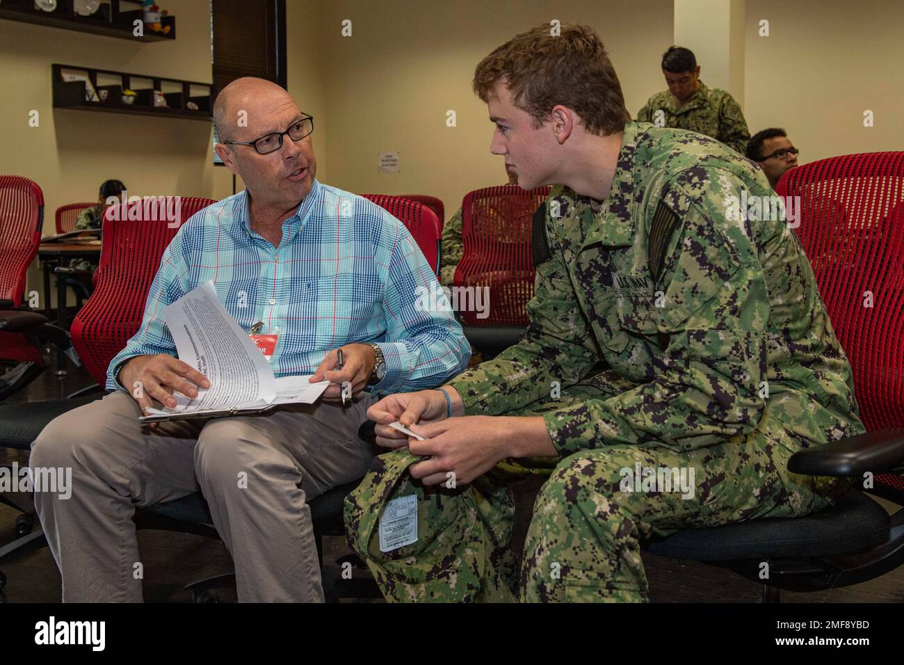 Raymond Torp, a staff member at Commander, Fleet Activities Sasebo (CFAS) Fleet and Family Support Center (FFSC), provides support to Fireman Luke Day at a simulated emergency family assistance center in the CFAS FFSC during Exercise Citadel Pacific 2022 (CP22) Aug. 18, 2022. CP22 is an annual exercise that is not in response to any specific real-world threat but is used to evaluate the readiness of fleet and installation security programs. Stock Photo