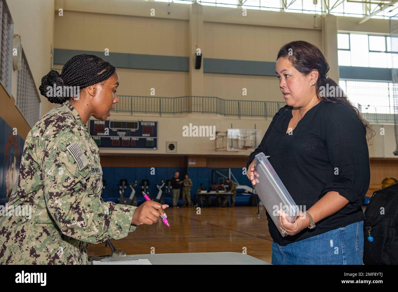 Yeoman 1st Class Amelia Franklin, assigned to Commander, Fleet Activities Sasebo (CFAS), speaks to Katherine Rocha during a simulated Non-combatant Emergency Operations (NEO) drill as part of Exercise Citadel Pacific 2022 (CP22) at CFAS Aug. 18, 2022. CP22 is an annual exercise that is not in response to any specific real-world threat but is used to evaluate the readiness of fleet and installation security programs. Stock Photo