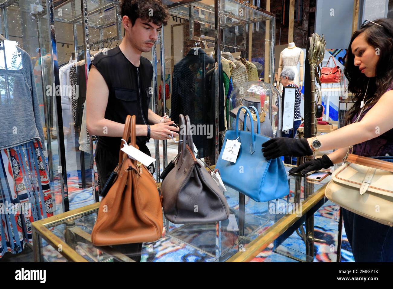 A male salesperson showing vintage Hermes handbags to customer in 2e Printemps (Second Printemps) the secondhand clothes and accessories store in 7ieme Ciel (Seventh Heaven) on the 7th floor of Au Printemps Haussmann.Paris.France Stock Photo