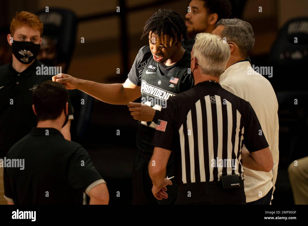 Providences Brycen Goodine, center, reacts to the stream of sunlight as Villanovas head coach Jay Wright, right, looks on with the official as it causes a delay in the start of the