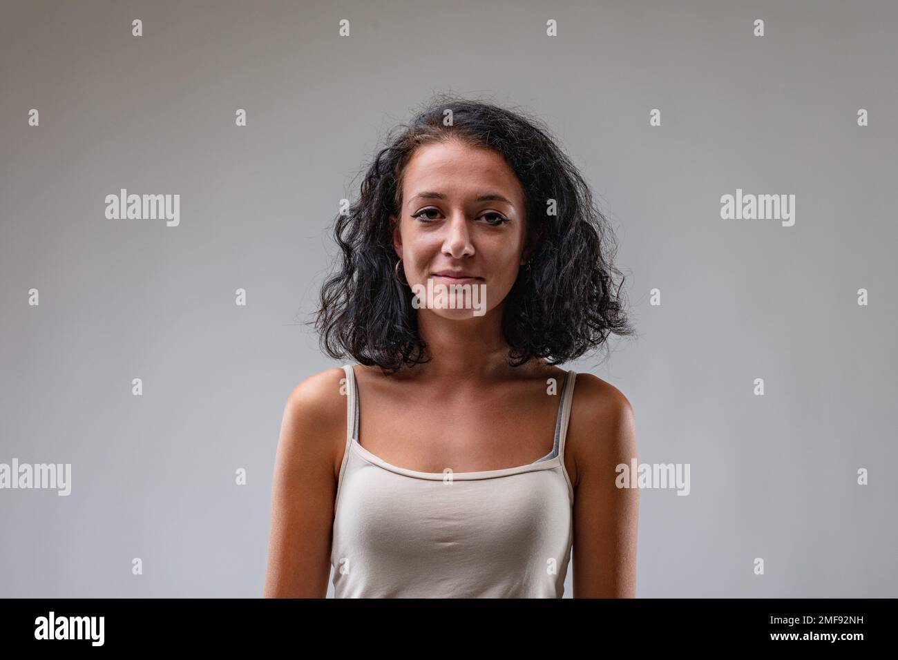 Frontal portrait of a young brunette girl in a tank top; she has a ...