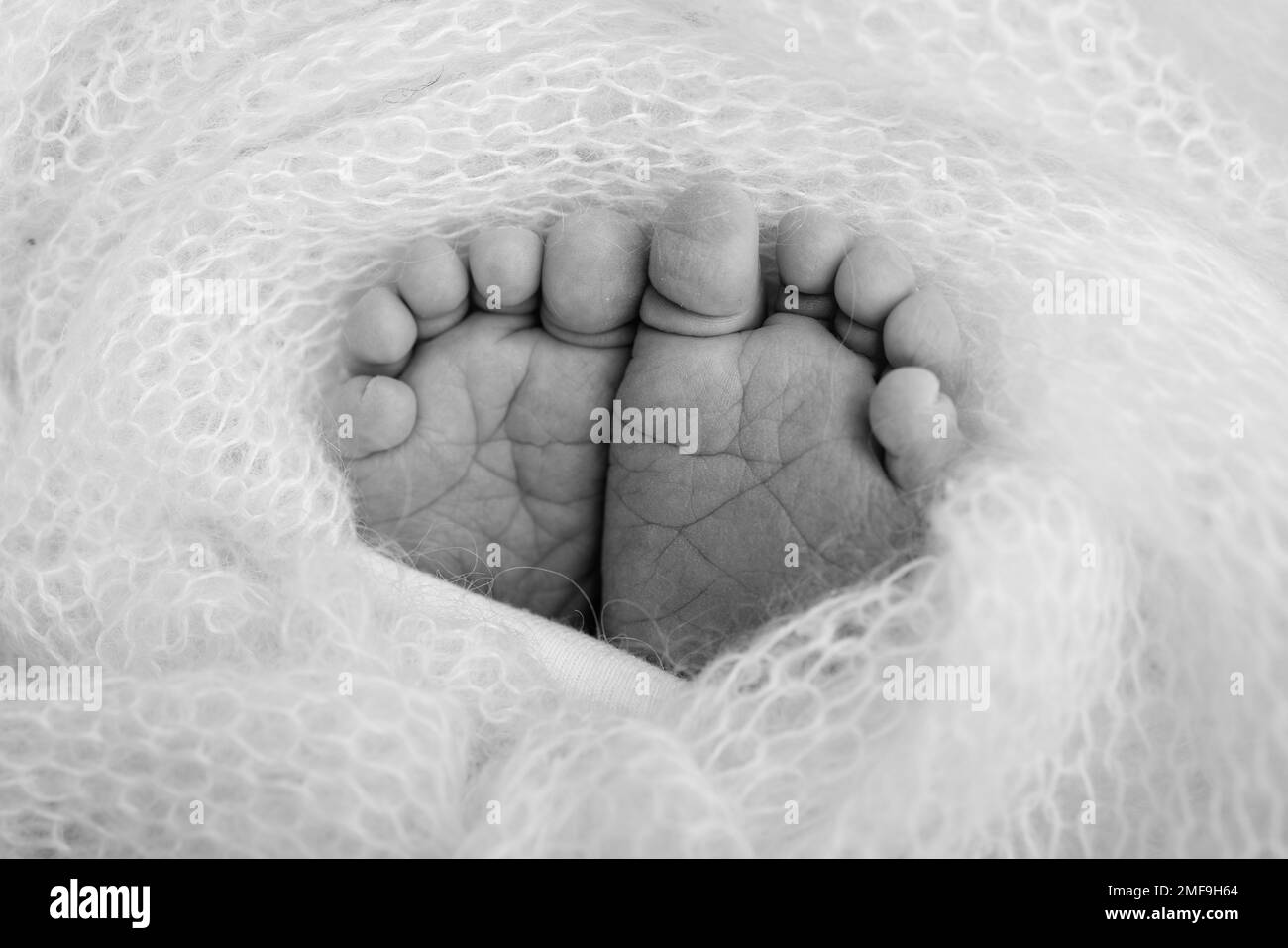 Baby foot on soft coverlet, blanket. Detail of a newborn baby legs