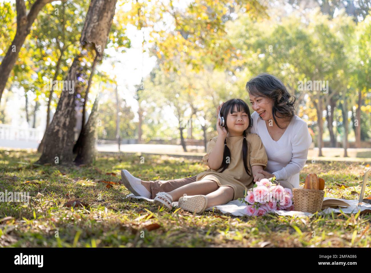 Happy Asian grandmother picnicking with her lovely granddaughter in park together. leisure and family concept Stock Photo
