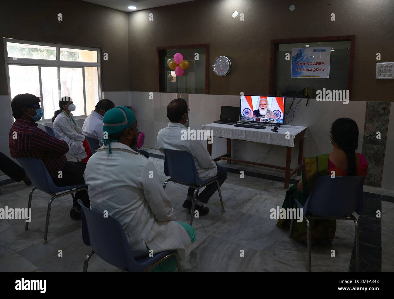 Indian doctors and hospital staff watch live telecast of Indian Prime Minister Narendera Modis address during the launch of the massive nationwide Covid-19 vaccination drive via video conferencing at a government Hospital