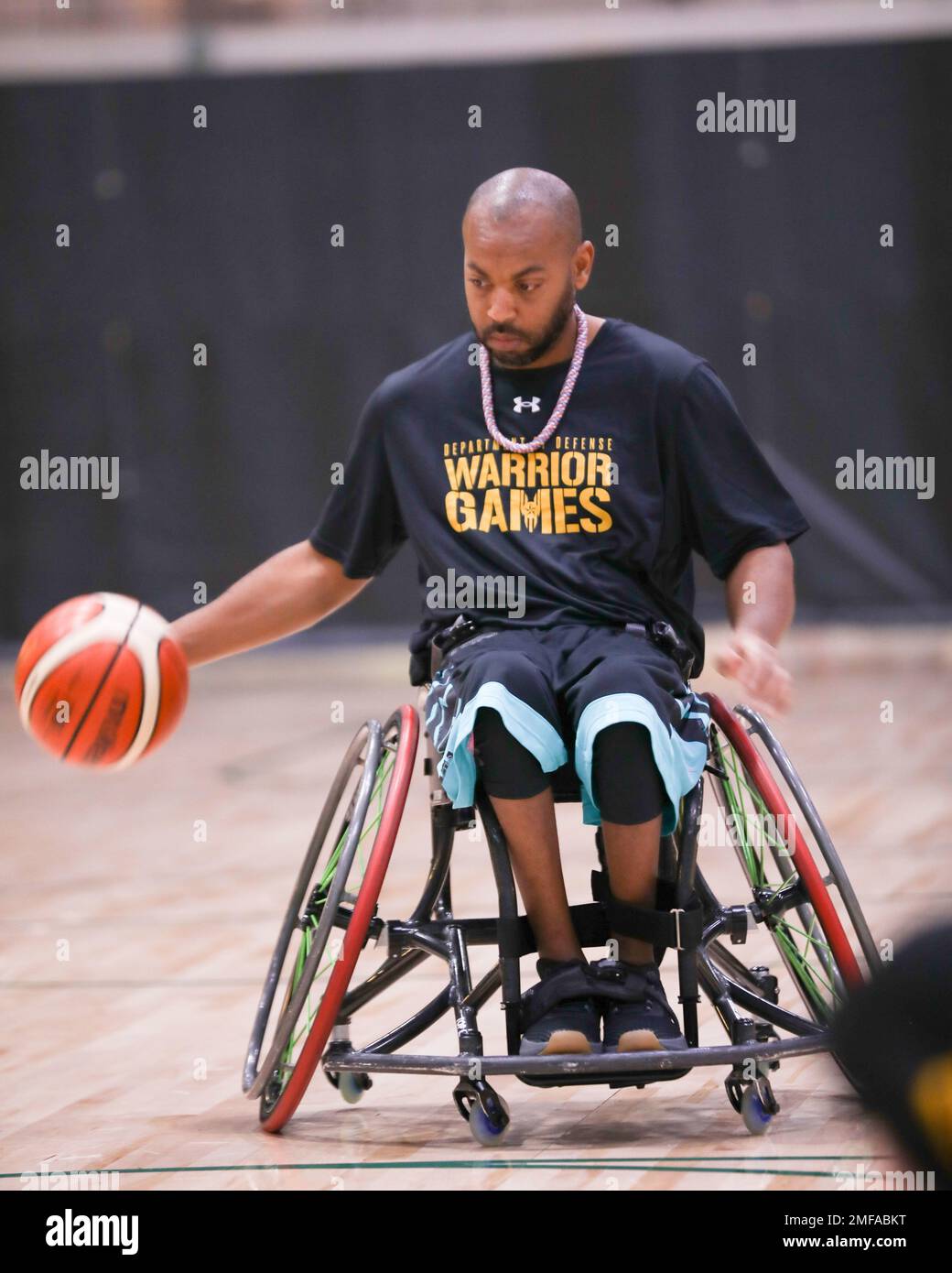 Retired U.S. Army Spc. Brent Garlic dribbles the ball at wheelchair  basketball practice during the 2022 Department of Defense Warrior Games at  the ESPN Wide World of Sports Complex in Orlando, Florida