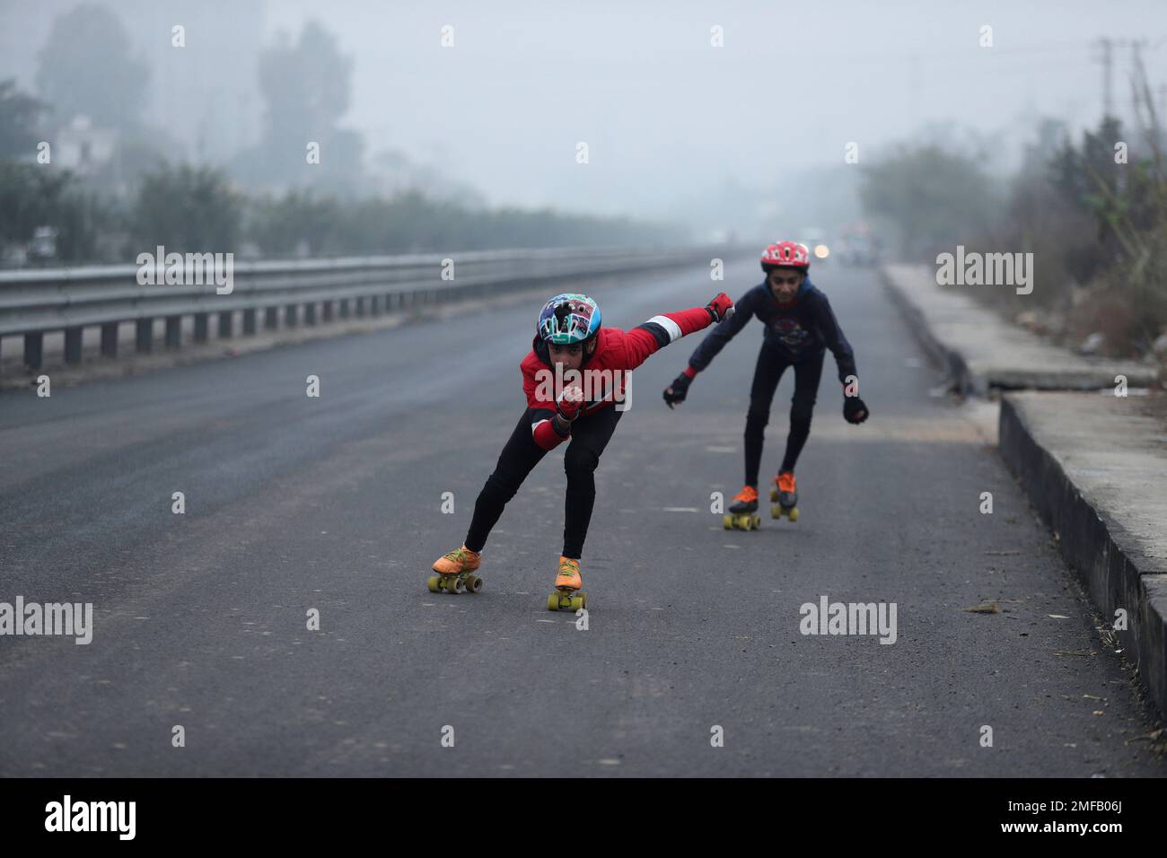 Boys skate on a road during a cold and foggy morning in Jammu, India,  Saturday, Jan. 9, 2021. Dense fog has disrupted rail, road and air traffic  in many parts of northern