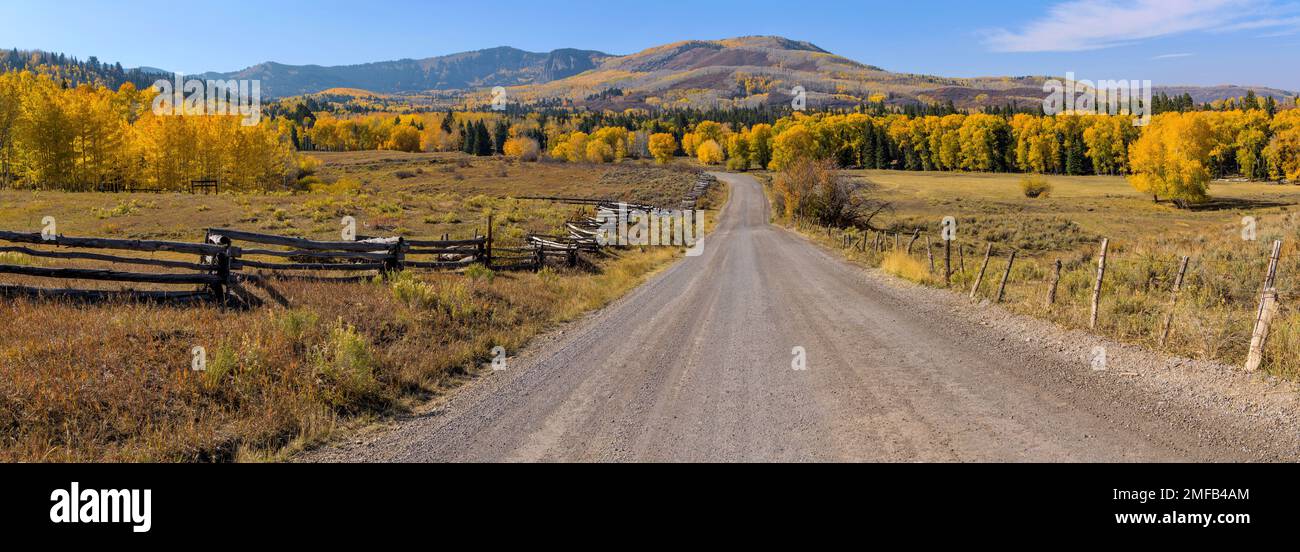 Autumn at Owl Creek Pass Road - Panorama of Owl Creek Pass Road running through rolling ranch land toward colorful mountain forest on an Autumn day. Stock Photo