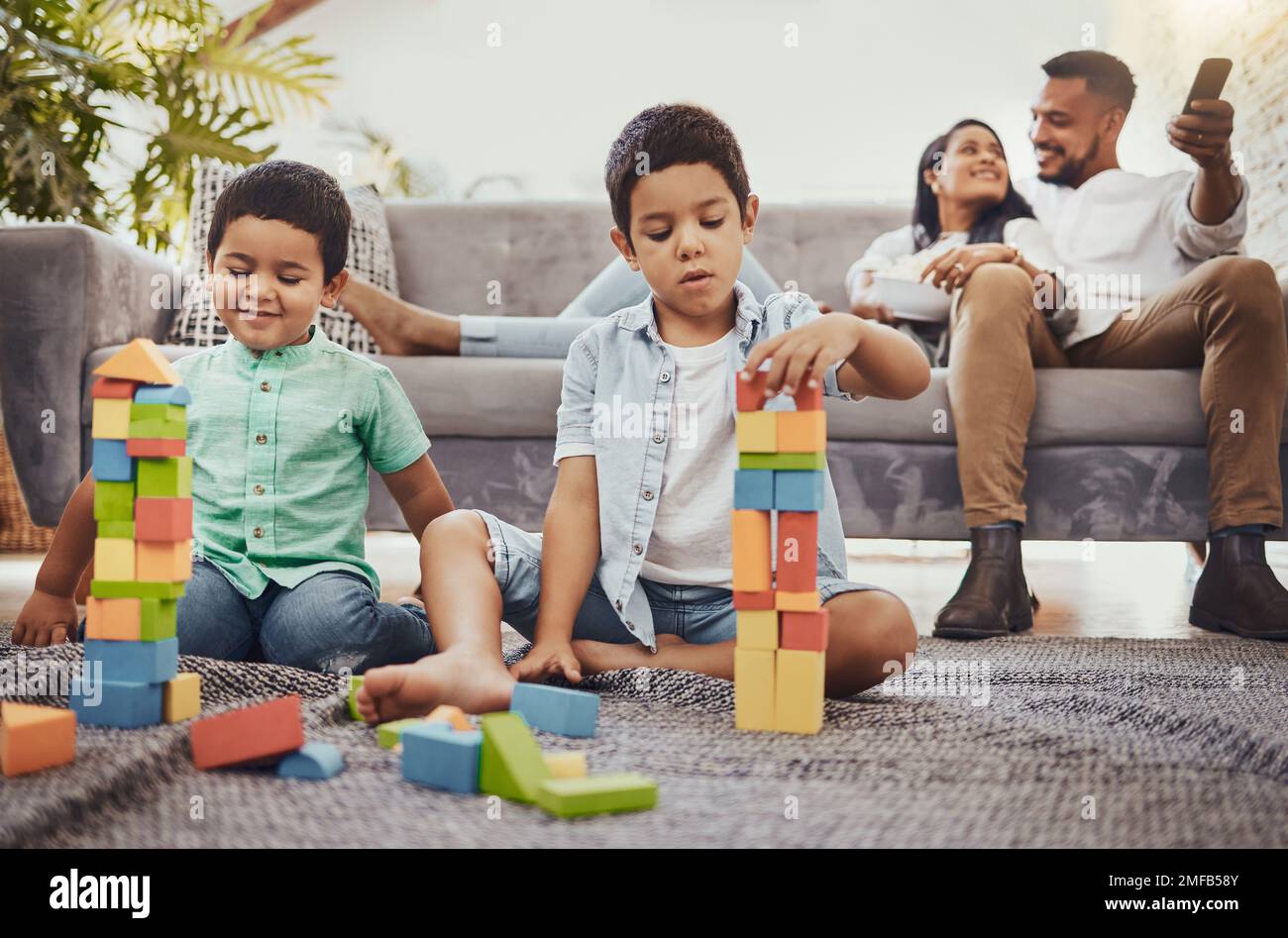 Family, toys and living room floor fun of children doing a learning knowledge development activity. Watching tv, parents and kids at home with love Stock Photo