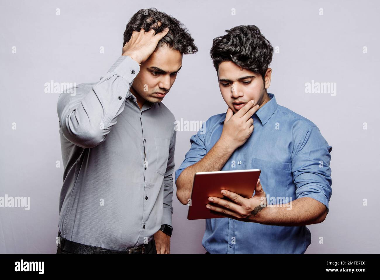 Sad despaired young Indian male managers looking at tablet screen, find