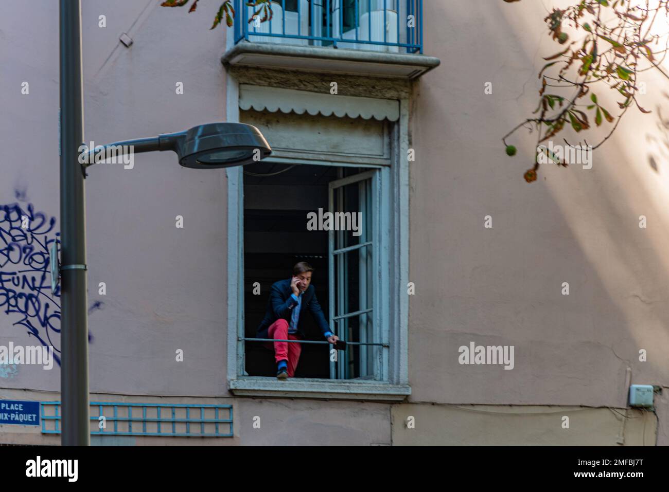 Man on phone while standing at the window in Lyon, France Stock Photo