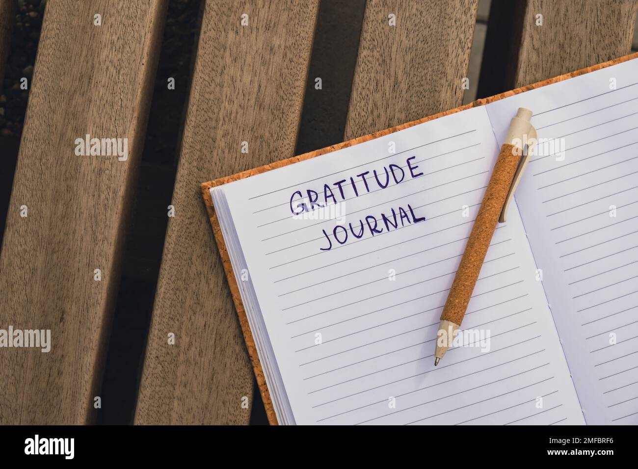 Writing Gratitude Journal on wooden bench. Today I am grateful for. Self discovery journal, self reflection creative writing, self growth personal development concept. Self care wellbeing spiritual health, being mindful, holistic health practices habits mindfulness  Stock Photo