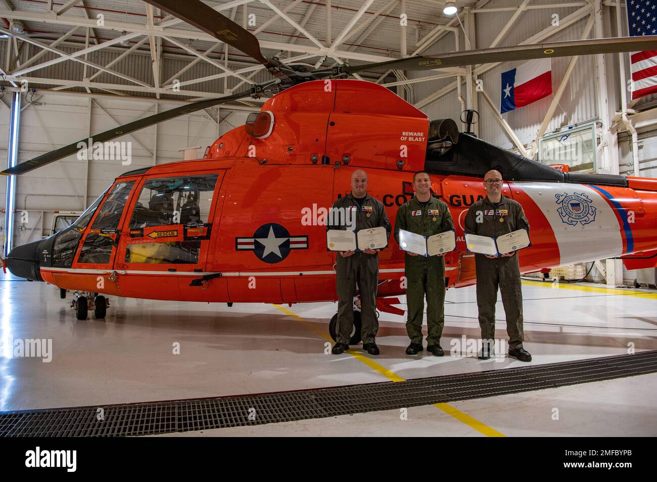 Cmdr. James Conner, an MH-65 Dolphin helicopter pilot, Petty Officer 1st Class Vincent Neiman, an aviation survival technician, and Petty Officer 2nd Class Christopher Collins, an aviation maintenance technician, pose for a photo after reciving Air Medals during an award ceremony at Coast Guard Air Station Houston, Texas, Aug. 19, 2022. During the ceremony, Rear Adm. Richard V. Timme, commander, Coast Guard District Eight, presented Conner, Neiman and Collins with Air Medals for rescuing nine trapped crew members from the Pride Wisconsin, a decommissioned mobile offshore drilling unit that cau Stock Photo