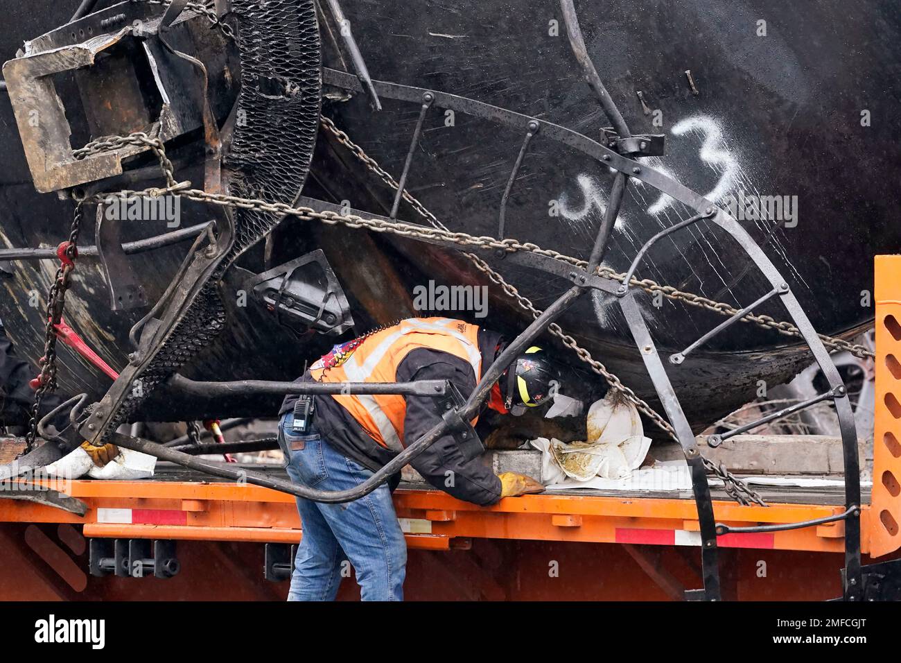 A worker cleans up residual oil leaking from an oil train car that