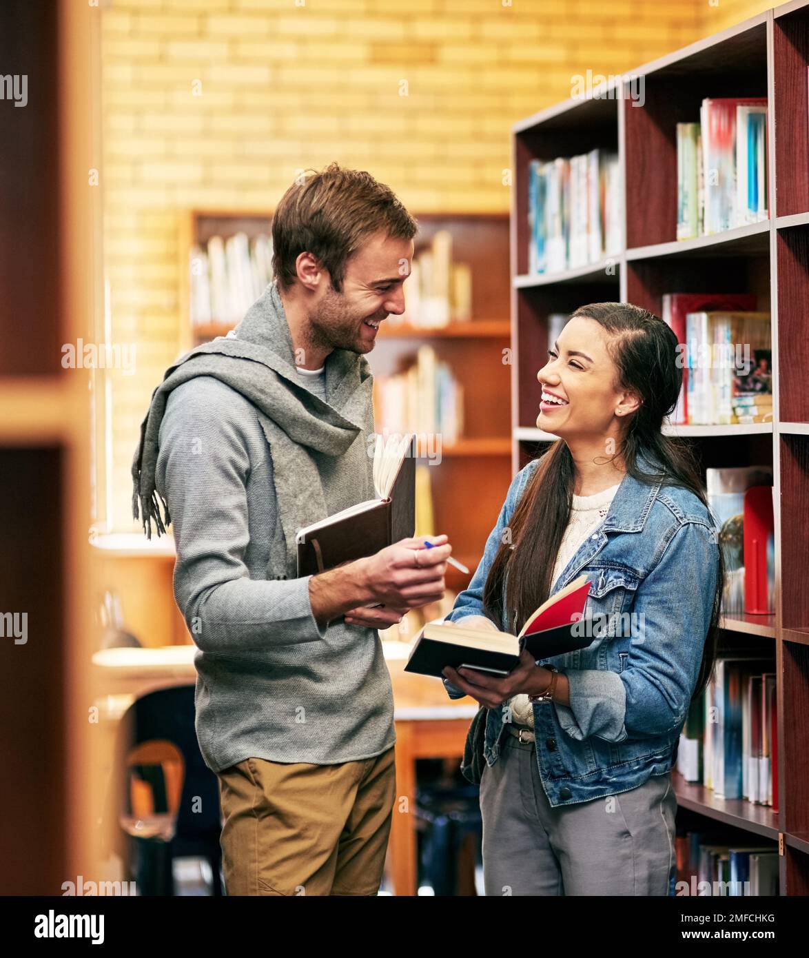 Working together can only strengthen your chance of succeeding. two university students working together in the library at campus. Stock Photo